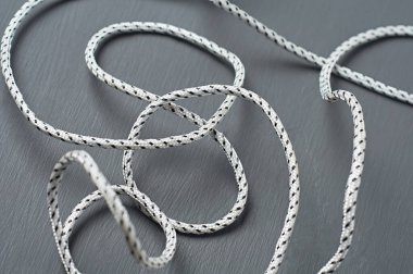 Dağınık siyah beyaz ip, koyu beton masanın üzerinde uzanıyor. Yakın plan.