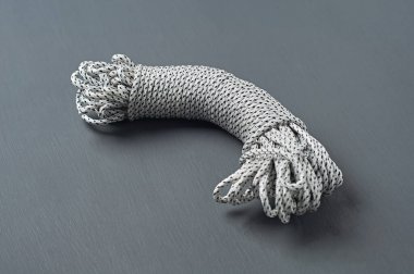 Siyah ve beyaz halat demeti koyu beton masa üzerinde uzanıyor. Yakın plan.