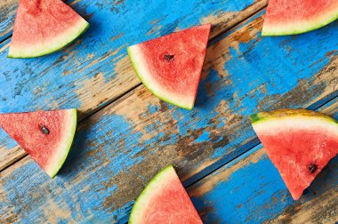 Dağıtılmış olgun sulu karpuz parçaları eski, yıpranmış mavi ahşap masanın üzerinde duruyor. Üst görünüm