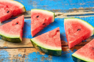 Çürümüş mavi ahşap masanın üzerinde tohumlu olgun sulu karpuzlar yatıyor. Yakın plan.