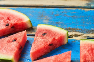 Çürümüş mavi ahşap masanın üzerinde tohumlu olgun sulu karpuzlar yatıyor. Metin için boşluk