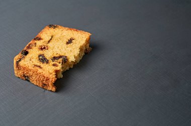 Kırık ev yapımı kuru üzümlü tatlı ekmeğin yarısı mutfaktaki koyu beton masada yatıyor. Metin için boşluk