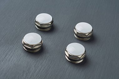 Bimetalik ya da alüminyum kalorifer için plastik halkalar ve beyaz plastik kapaklı altıgen metal fındık formundaki yeni koçanlar atölyedeki koyu beton masada yatıyor. Yakın plan.