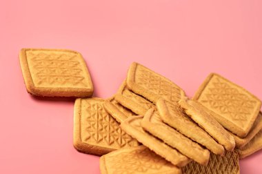 Mutfaktaki pembe masanın üzerine saçılmış kare kurabiyeler. Metin için boşluk