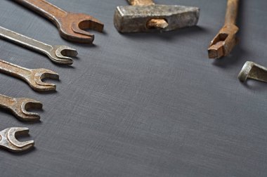 Farklı eski paslı ve pis aletler koyu betonun üzerinde yatıyor. Metin için boşluk