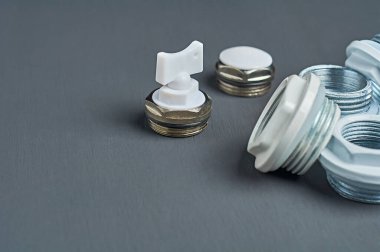 Eve ısıtma sistemi kurmak için kullanılan metal fındık ve valf seti atölyedeki koyu beton masada yatıyor. Metin için boşluk