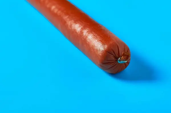 Une Longue Saucisse Entière Repose Sur Fond Bleu Sur Cuisine — Photo