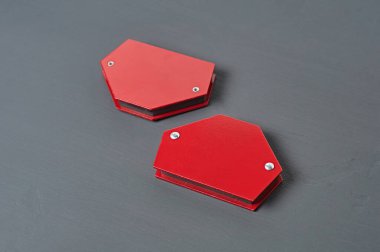 Kaynak yapmak için metal parçaları onarmak için bir çift mıknatıs köşesi atölyedeki koyu beton masada yatıyor. Yakın plan.