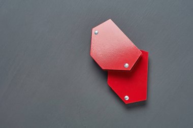 Kaynak yapmak için metal parçaları onarmak için bir çift mıknatıs köşesi atölyedeki koyu beton masada yatıyor. Mesaj için yer var. Üst görünüm