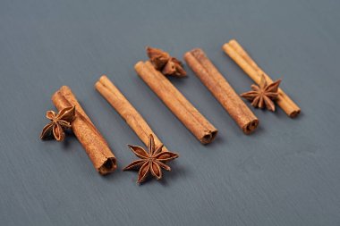 Anasonlu yıldızların yanındaki beş aromalı tarçınlı çubuklar mutfaktaki koyu çizik masasında yatıyor. Yakın plan.