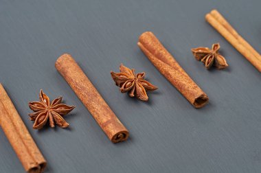 Anasonlu yıldızların yanındaki beş aromalı tarçınlı çubuklar mutfaktaki koyu çizik masasında yatıyor. Yakın plan.