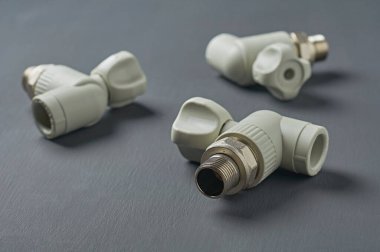 Atölyedeki koyu beton masaya radyatör ısıtmak için üç polipropilen su musluğu serptim. Yakın plan.