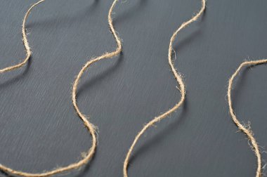 Eski kıvırcık kahverengi ip atölyedeki koyu beton masanın üzerinde yatıyor. Yakın plan.