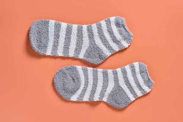 Pair of striped soft and warm socks on orange background. Top view. Close-up