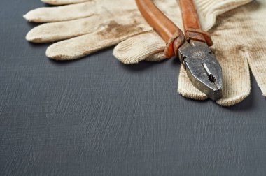 Tamir ya da diğer zor işler için bir çift kirli tekstil koruyucu eldiven plastik saplı eski dağınık kerpeten yakınında çalışma odasındaki koyu çizik beton masada yatıyor. Metin için alanı kopyala