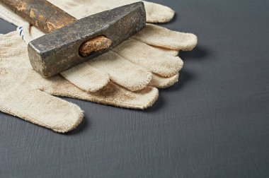 Tamir için bir çift kirli tekstil koruyucu eldiven ya da ahşap saplı eski dağınık çekiç yanında çalışma odasındaki koyu çizik beton masada yatıyor. Metin için alanı kopyala