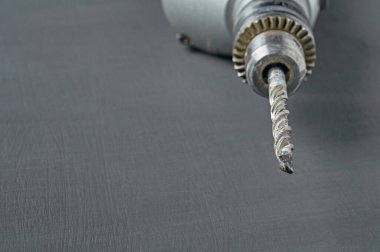 Tamir için eski ve kirli bir elektrikli matkap ya da çengelli delgi veya diğer ağır işler atölyedeki koyu beton masada yatıyor. Metin için boşluk