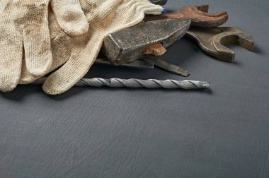 Tamir için bir çift kirli tekstil koruyucu eldiven ya da çalışma odasındaki koyu çizik beton masa üzerinde duran eski ve karmaşık aletlerle yapılan diğer sıkı işler. Mesaj için yer var. Üst görünüm