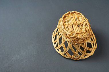 Ekmek, meyve ve diğer gıda ürünleri için ters dönmüş boş bir oval ahşap hasır sepet koyu çizilmiş beton masanın üzerinde yatıyor. Metin için boşluk