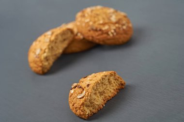 Ayçiçeği tohumlu ve susamlı bütün ve kırılmış ev yapımı kurabiyeler mutfaktaki koyu çizik beton masada yatıyor. Yakın plan.