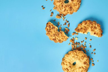 Mutfaktaki mavi masanın üzerinde fıstıklı ve kırıntılı taze yuvarlak yulaf kurabiyeleri duruyor. Mesaj için yer var. Üst görünüm