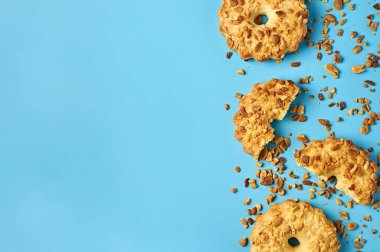 Mutfaktaki mavi masanın üzerinde fıstıklı ve kırıntılı taze yuvarlak yulaf kurabiyeleri duruyor. Mesaj için yer var. Üst görünüm