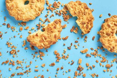 Mutfaktaki mavi masanın üzerinde fıstıklı ve kırıntılı taze yuvarlak yulaf kurabiyeleri duruyor. Üst Manzara. Yakın plan.