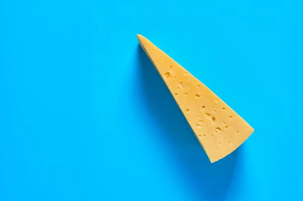 Een Stuk Kaas Vorm Van Een Driehoek Ligt Een Blauw — Stockfoto