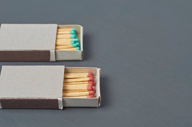 Mutfaktaki koyu beton masada üzerinde kırmızı ve yeşil sülfür bulunan iki kibrit kutusu. Metin için boşluk