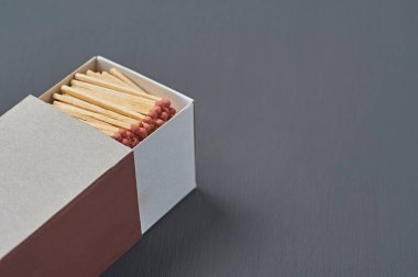 Mutfaktaki koyu beton masada kırmızı sülfür bulunan bir sürü kibrit çöpünden oluşan büyük bir karton kutu. Metin için boşluk