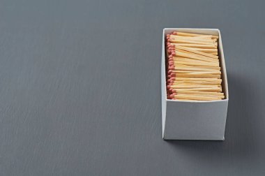 Mutfaktaki koyu beton masada kırmızı sülfür bulunan bir sürü kibrit çöpünden oluşan büyük bir karton kutu. Metin için boşluk