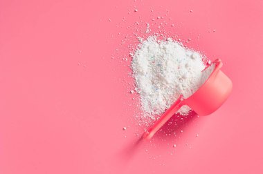 Plastik kaşıktan dökülen bezi temizlemek için kullanılan deterjan, çamaşırhanedeki pembe tezgahın üzerinde yatıyor. Mesaj için yer var. Üst görünüm
