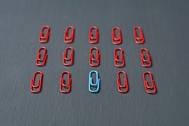 Ofis işi ya da eğitim için kırmızı renkli ataçlar ve koyu renkli beton bir masa üzerinde mavi yalanlar. Ayrılma ya da kimlik kavramı. Yakın plan.