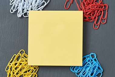 Ofis işi ya da eğitim için dört toka ataç ve merkezdeki boş kare çıkartma koyu çizik beton masada yatıyor. Ayrılma ya da kimlik kavramı. Yakın plan. Metin için boşluk