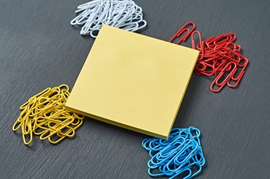 Ofis işi ya da eğitim için dört toka ataç ve merkezde boş bir kare çıkartma koyu çizik beton masa üzerinde yatıyor. Ayrılma ya da kimlik kavramı. Yakın plan. Metin için boşluk