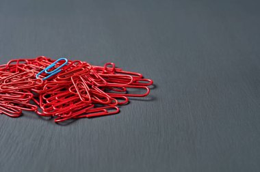Ofis işi ya da eğitim için bir sürü kırmızı ataç yığını üzerinde koyu renkli çizik beton masa uzanıyor. Ayrılma ya da kimlik kavramı. Metin için boşluk