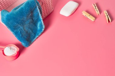 Antibakteriyel sabunun yanında yumuşak havluyla yıkanmak için plastik sepet, toka ve pudra dolu ölçü kaşığı çamaşırhanenin pembe tezgahında yatıyor. Metin için boşluk