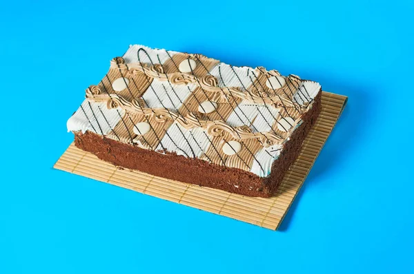 Jeden Cały Kratkę Prostokątny Tort Bambusowej Macie Leży Niebieskim Stole — Zdjęcie stockowe