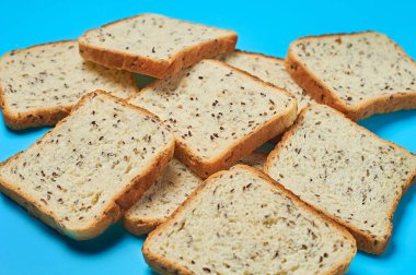 Ekmek için tohum ekilmiş bir yığın kare ekmek mutfaktaki mavi masada yatıyor. Yakın plan.