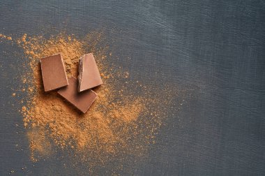 Koyu çizikli beton masaya saçılmış bir yığın acı ya da sütlü kakao tozu. Mesaj için yer var. Üst görünüm