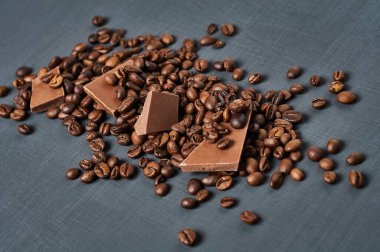 Koyu çizik beton masaya saçılmış kahve çekirdekli acı ya da sütlü çikolata yığını. Yakın plan.