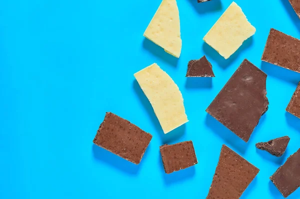 様々な多孔質チョコレートバーの散乱部分はキッチンの青いテーブルの上にあります テキスト用のスペース トップ表示 — ストック写真