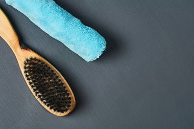 Temizlik için ahşap saplı ya da yuvarlanmış mavi havlunun yanındaki ayakkabılı bir ters fırça banyodaki koyu beton masada yatıyor. Üst Manzara. Metin için boşluk