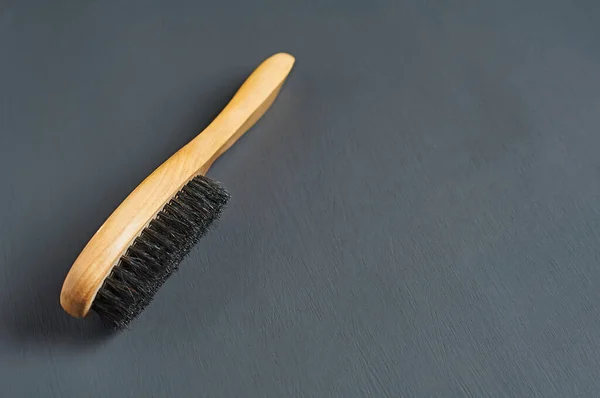 One brush with wooden handle for cleaning clothes or footwear lies on dark concrete desk in bathroom. Space for text