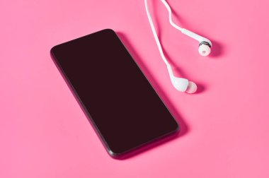 Portatif beyaz kulaklık, akıllı telefon ya da pembe arka planda tablet. Video arama kavramı