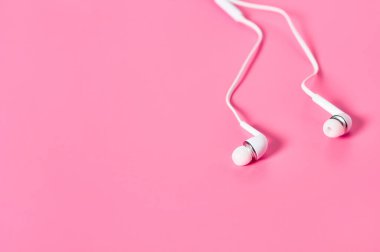 Akıllı telefon veya pembe arka planda ses oynatıcı için taşınabilir beyaz kulaklıklar