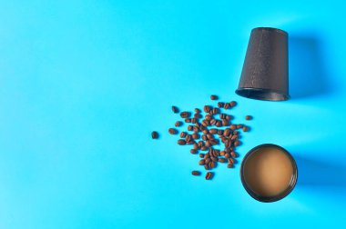 Mavi arka planda dağınık fasulyelerin yanında tam siyah karton kahve bardağı. Uzayı kopyala Üst Manzara. Çevre koruma kavramı, kırılma, ekoloji