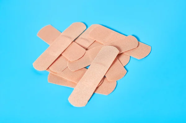 Heap of sticky medical patches on blue background. Healthcare concept