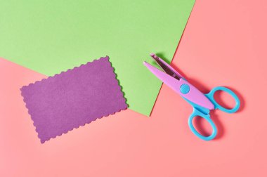 Dekoratif kıvrımlı kağıt kesme makası ve pembe zemin üzerinde dalga sınırı olan el işi için boş kağıtlar. El yapımı, boş zaman ve anaokulu eğitimi kavramı