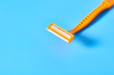 Mavi arka planda tüy dökümü için tek kullanımlık kadın jileti. Cildine dikkat et. Güzellik konsepti